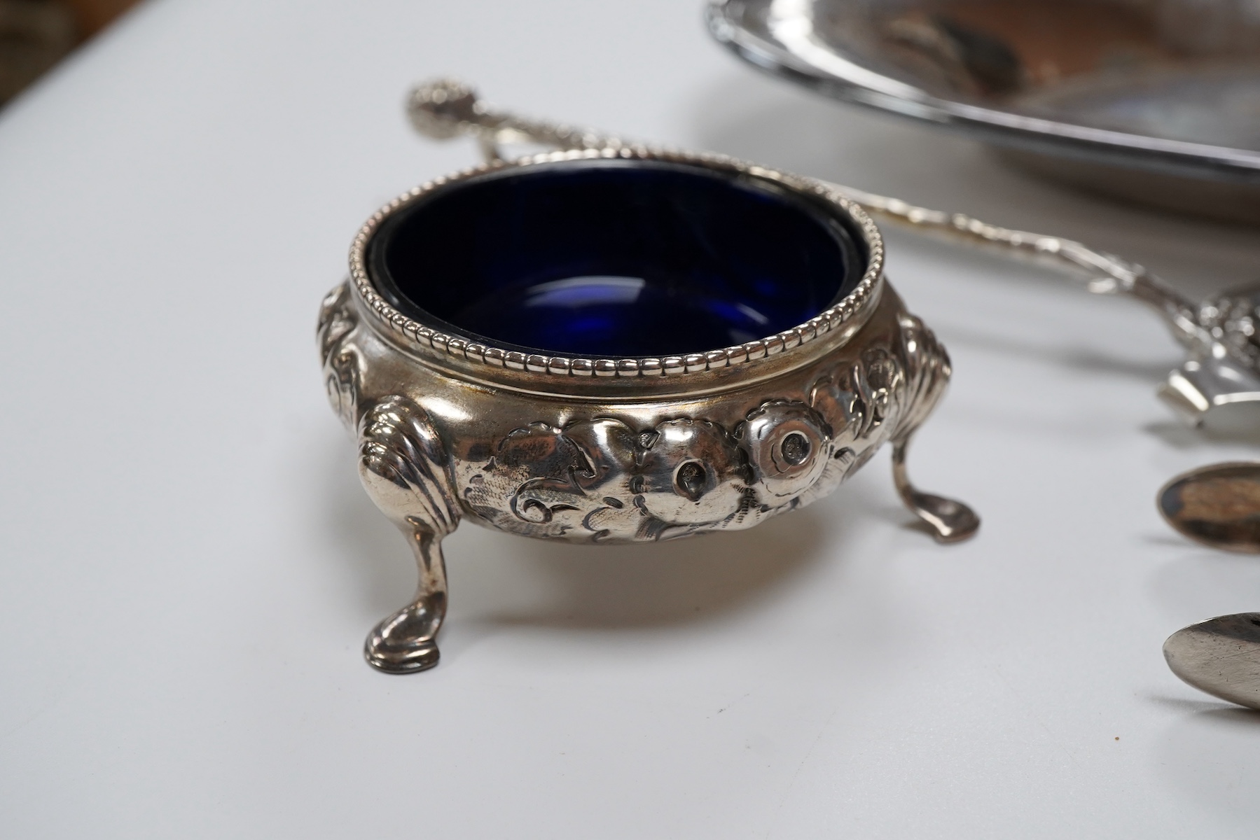 A Victorian silver bun salt, London, 1860, a later silver cigarette case, a silver napkin ring and pair of silver sugar tongs, together with a continental white metal serving spoon and a silver plated oval tray.